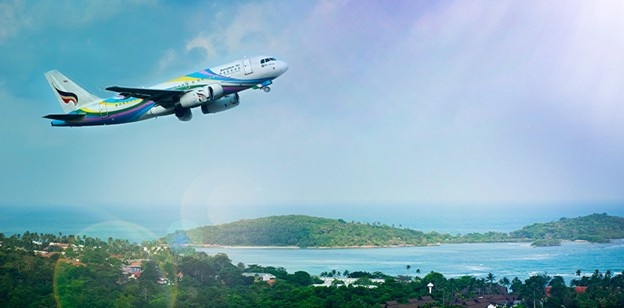 Airplane taking off above tropical island beach with clear blue ocean and scenic landscape